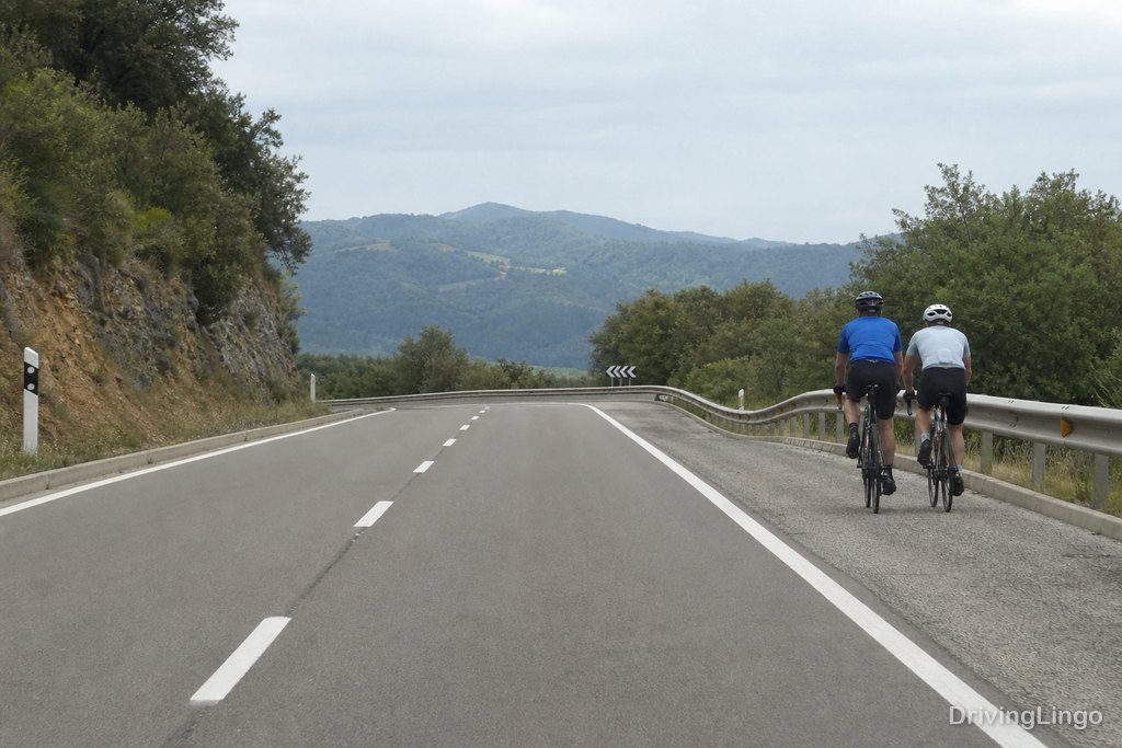 Ciclista circulando por el arcén de una carretera