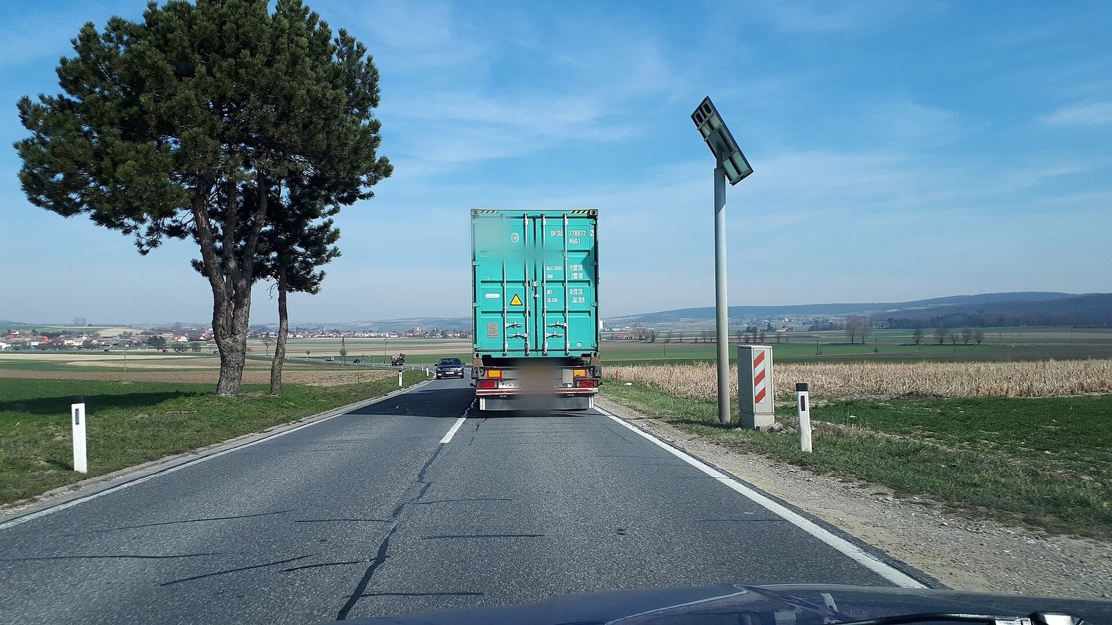 Camión con un contenedor circulando por una carretera rural