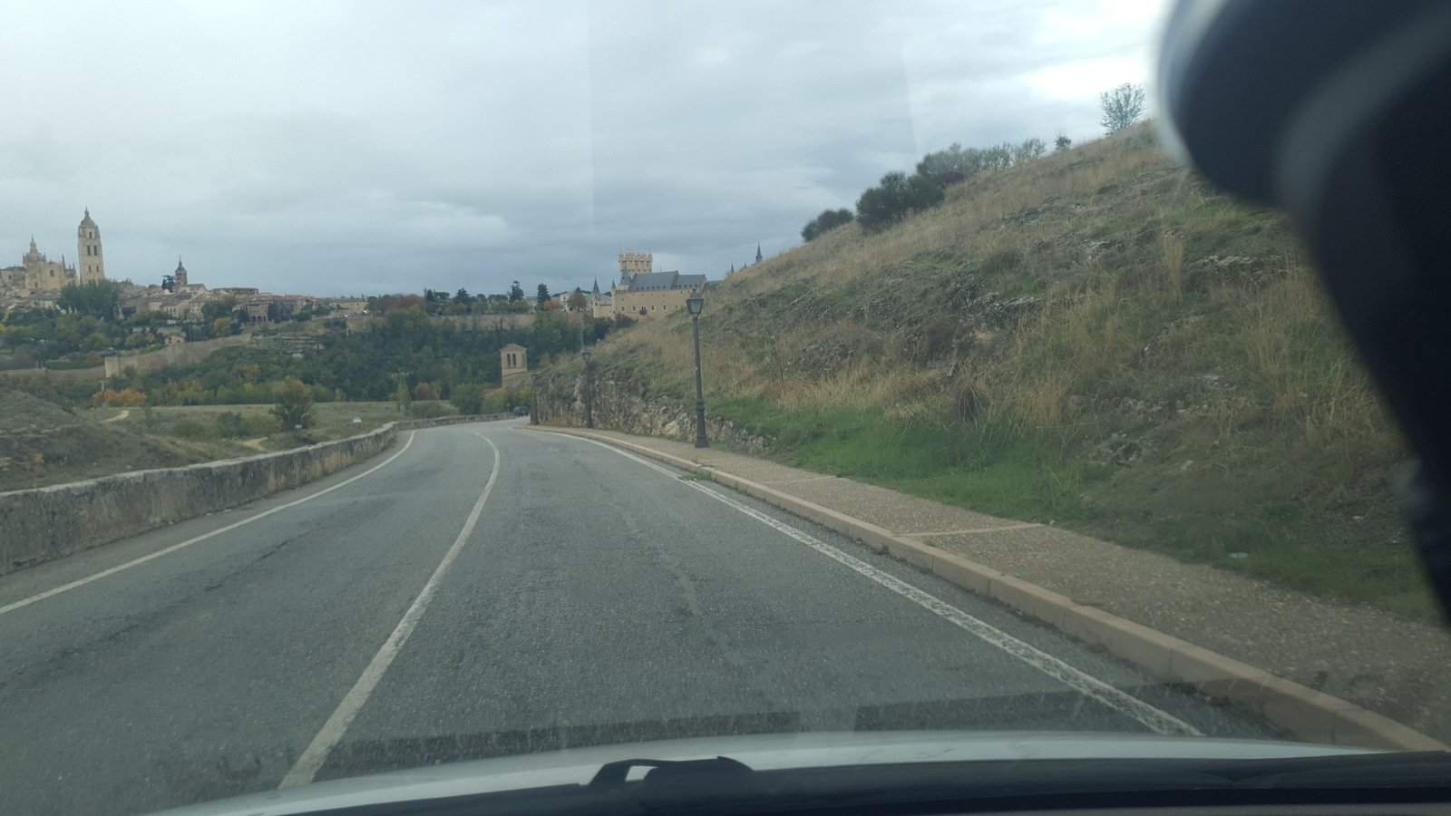 Carretera convencional de dos carriles que sube hacia un cambio de rasante que oculta el trazado