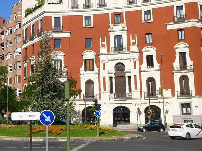 Glorieta urbana de Madrid con semáforos en postes verdes en sus accesos, vista desde un acceso