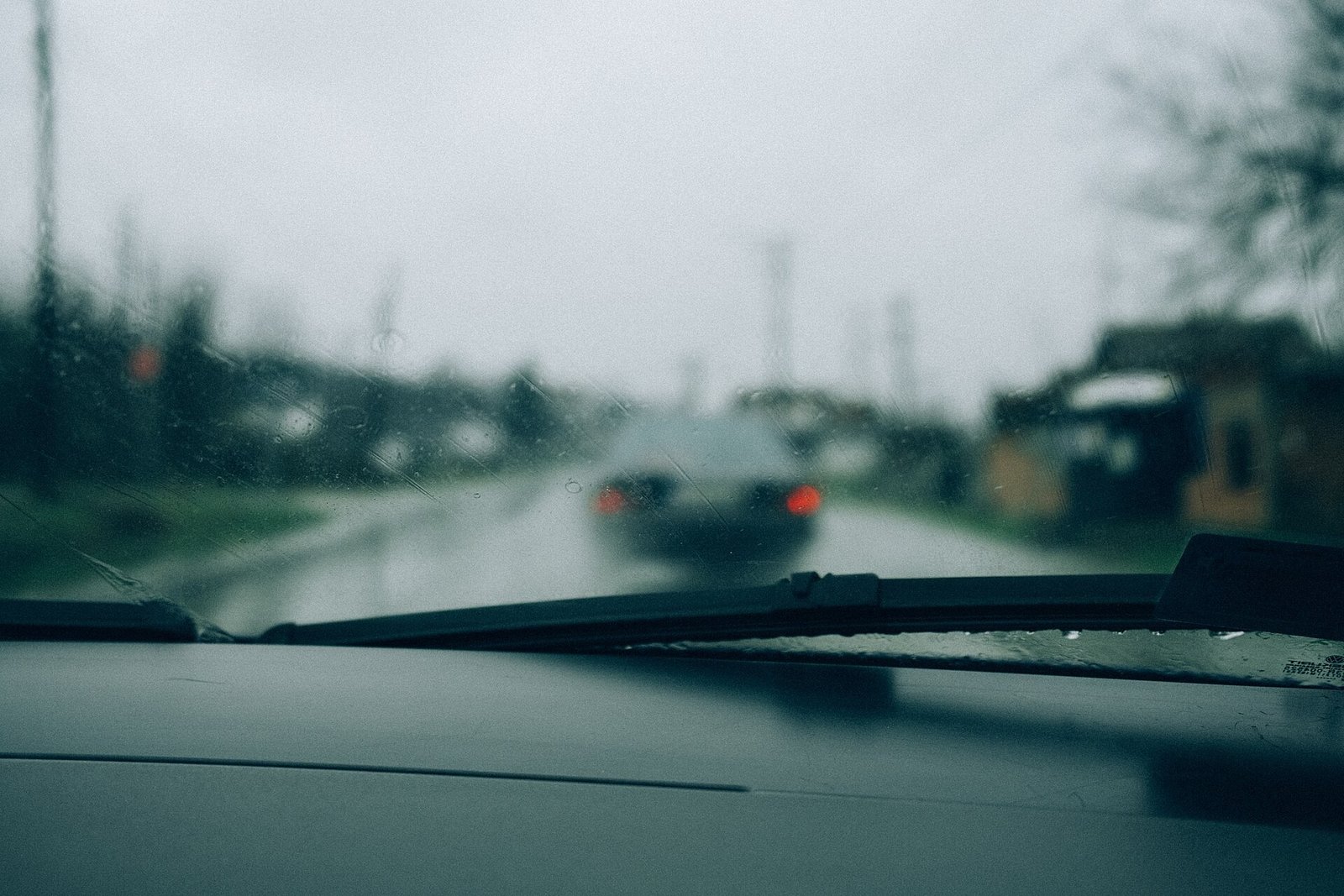 Carretera mojada vista a través de un parabrisas con gotas de lluvia