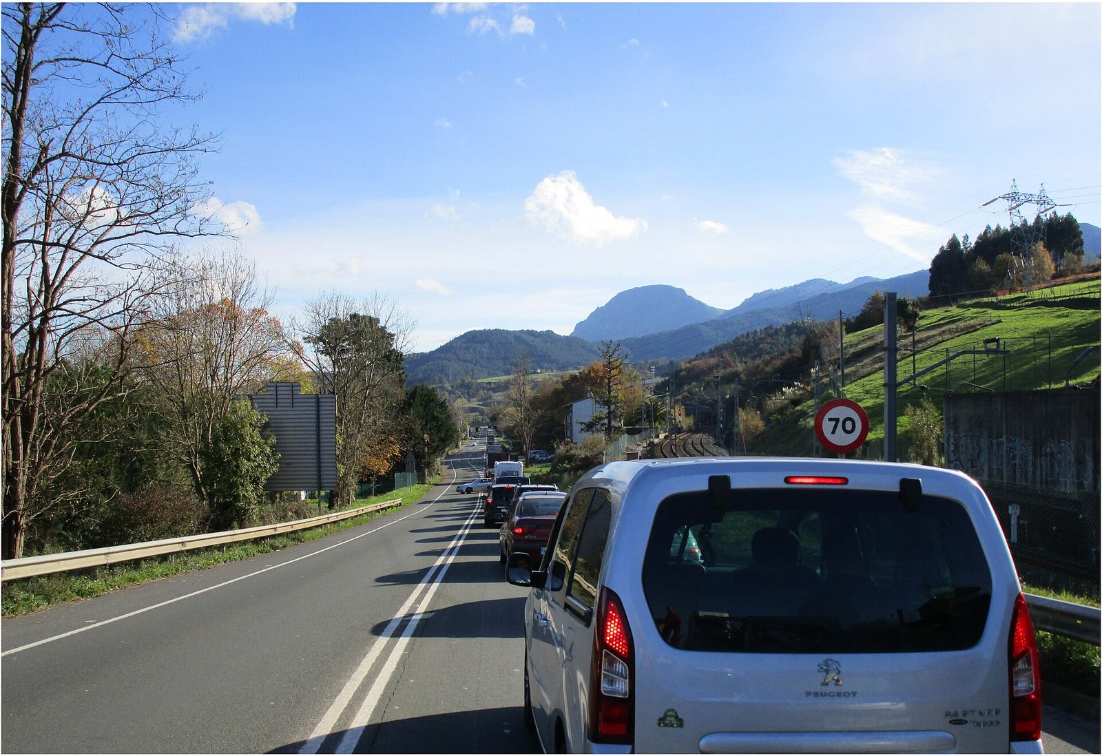 Vehículos circulando en cola muy próximos por una carretera, con luces de freno encendidas